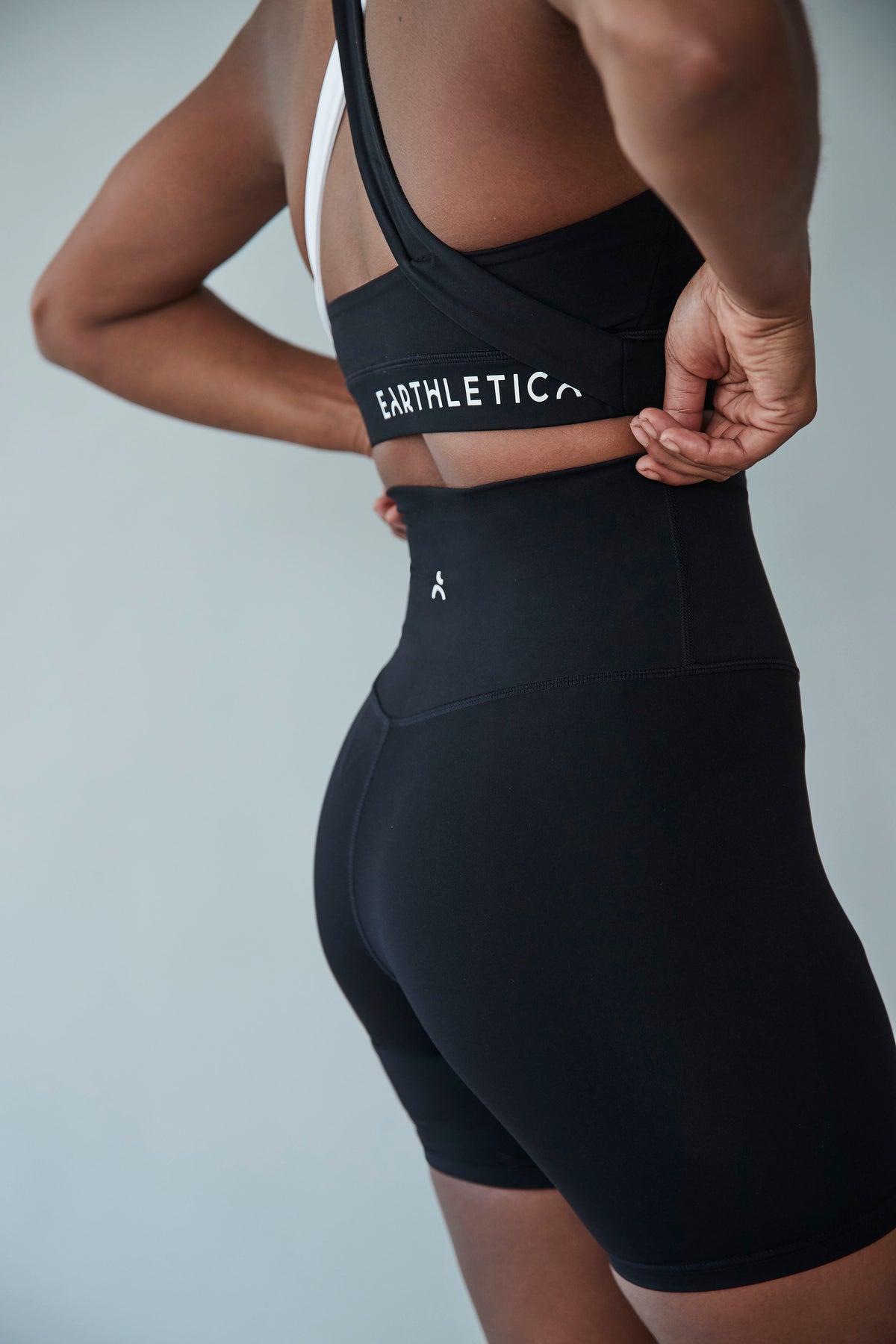 A close up shot of a model wearing the Star Drop Crop and Midnight Bike Shorts from Earthletica. She is photographed from behind, adjusting the waist of the bike shorts.