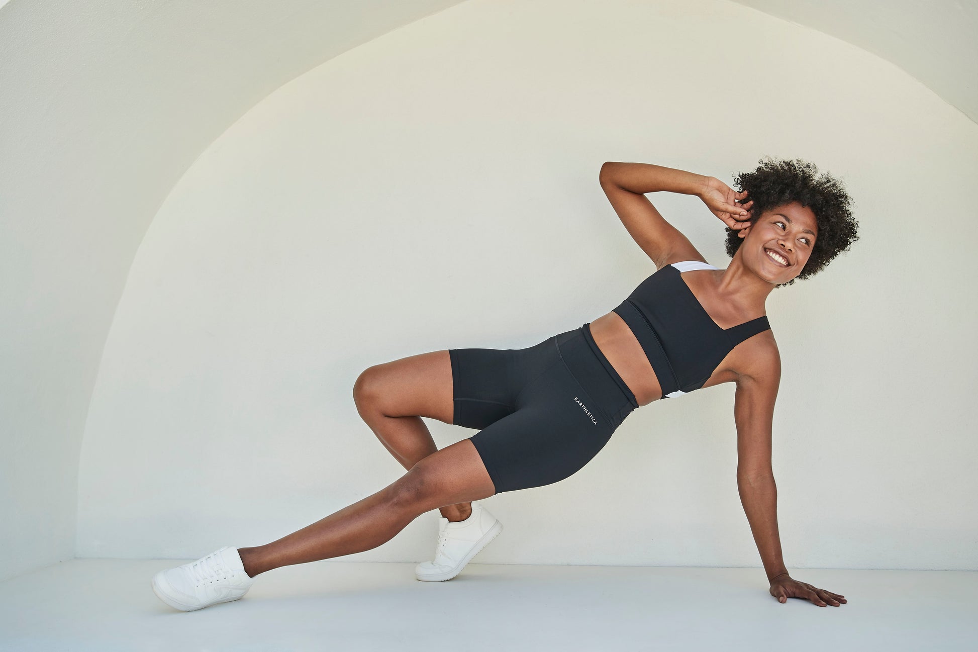 An Earthletica model wearing the Star Drop Crop + Midnight Bike Shorts and smiling while engaged in exercise.